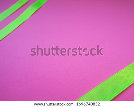 Three green satin ribbons at the corners on a pink background