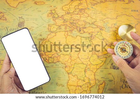 Travel accessories concepts : It's time to go to travel around the world - The image of a world map with essentials accessories - smart phone and compass. Vintage tone style. Top view picture.