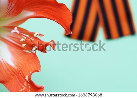 Ribbon of St. George and orange lily flower on the background for Victory Day. May 9, 2020 - 75 years of Victory in the Great Patriotic War. Flat lay, copy space, top view.