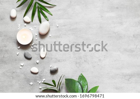 Spa concept on stone background, palm leaves, candle and zen, grey stones, top view, copy space.