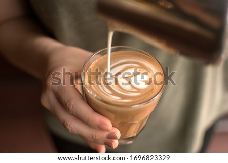 Pouring latte art into the flat white glass Royalty-Free Stock Photo #1696823329