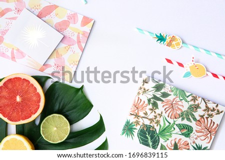 Creative flat lay with Exotic tropical monstera palm leaf and home office stationery on minimal background with summer fruits. 