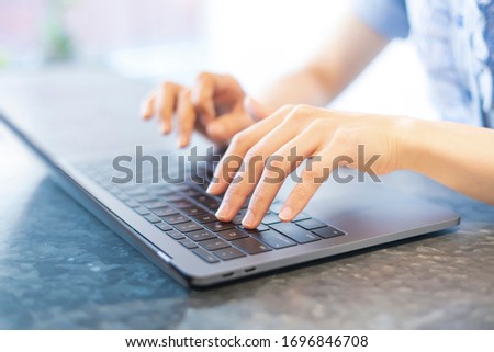 Close-up photo of female hands typing on keyboard at indoor workplace
