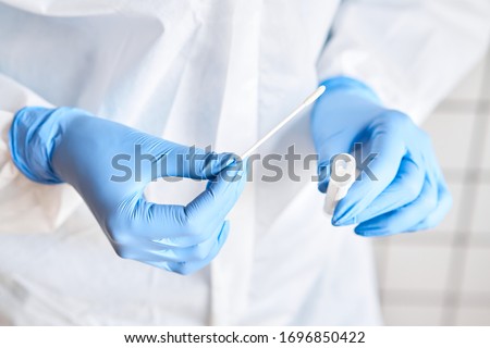 Doctor holding swab test tube for 2019-nCoV analyzing. Coronavirus test. Blue medical gloves and protective face mask for protection against covid-19 virus. Coronavirus and pandemic.