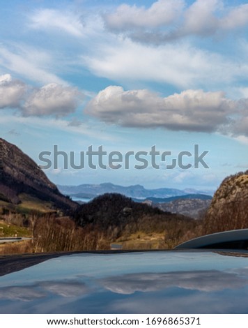 Reflection of floating clouds across the sky on the roof of a car