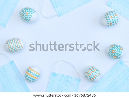 Decorated Easter eggs with medical face masks on white background with copy space. Happy Easter during quarantine concept. Biohazard, 2019-nCoV, COVID-19, social distance, stay home. Flat lay.