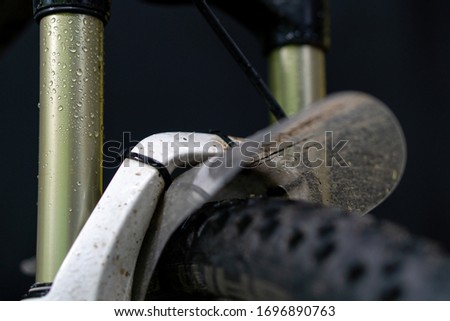 Drops of water on a bicycle fork close-up. Fork and tire mountain bike on a black background. splash protection on the front wheel.
