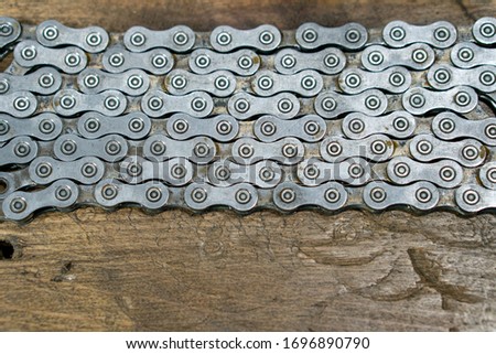 A dirty rusty Bicycle chain is placed on a wooden table. Bicycle repair shops. New and old bicycle components