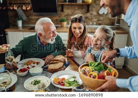 Happy extended family having fun while talking during lunch in dining room. Focus is on little girl.  Royalty-Free Stock Photo #1696890898