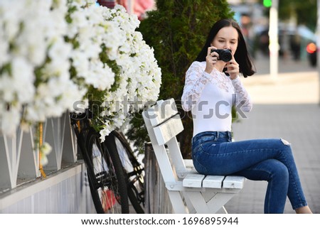 Young brunette woman, novice photographer, with modern compact digital camera takes pichures
