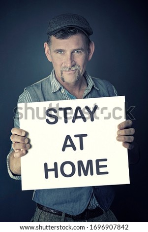 stylish man holding a sign with the words Stay At Home