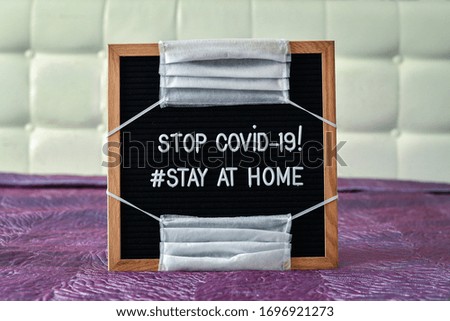 'Stop COVID-19 stay at home' words on a letterbox with virus protective masks, standing in the bedroom.   