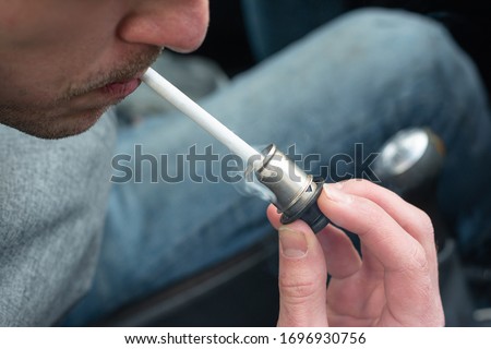 a man lights a cigarette with an electronic cigarette lighter in a car. bad habits. inside the car Royalty-Free Stock Photo #1696930756