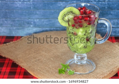 Delicious fruit dessert of kiwi, pomegranate and lime juice in a glass goblet with a handle.