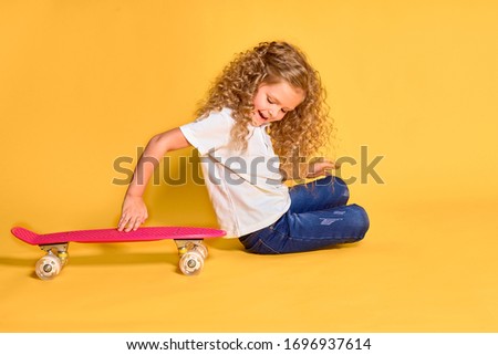 Active and happy girl with curly hair, headphones having fun with penny board, smiling face stand skateboard. Penny board cute skateboard for girls. Lets ride. Girl with penny board yellow background.