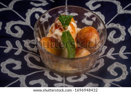 mini fried cakes with sugar and traditional cinnamon from Brazil where they are called a bolinho de chuva. Pictured is served with cream ice cream with blue patterned background