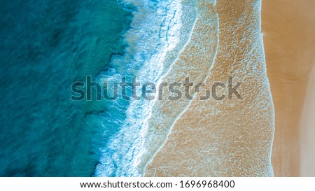 Top down aerial view of beach with waves crashing into the sand during day time