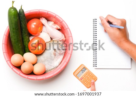 A flatlay picture of groceries and necessity food in the basin with hand written on notebook and calculator. Panic buying happen around the world caused by covid-19 lockdown.