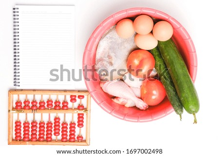 A flatlay picture of groceries and necessity food in the basin with notebook and abacus insight. Panic buying happen around the world caused by covid-19 lockdown.