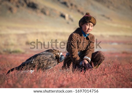Traditional young kazakh eagle huntress with her golden eagle that is used to hunt for fox and rabbit fur. Ulgii, Western Mongolia.