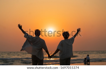 Elderly couple moments of relaxation with a happy picture impression. Tour. Portrait of a middle-aged man and women standing holding hands by the sea in the evening.