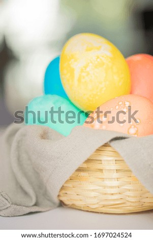 Hand-painted Easter eggs of different colors in a wicker basket on a white table. Close-up