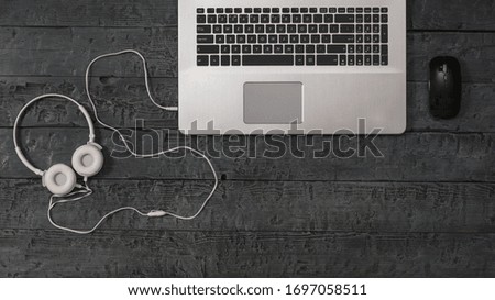 White headphones, mouse and laptop on a wooden background. The concept of workplace organization. Equipment for recording, communication and listening to music. Flat lay.