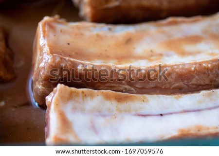 Raw marinaded juicy pork ribs ready for cooking. Meat processing picture. Food photography close up background