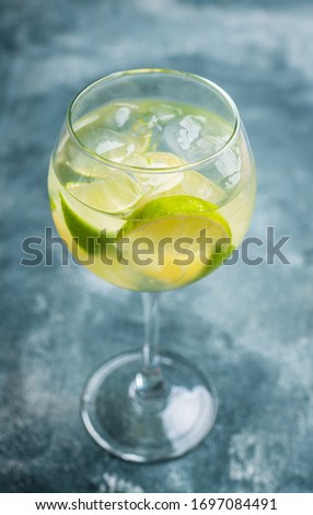 Rum based cocktail with lime in wine glass (variation of cuba libre) on the rustic background. Selective focus. Shallow depth of field.