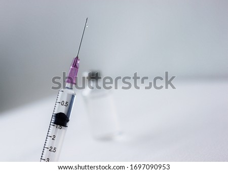 A syringe with Blured background of Medical vials for injection  and ampules on white background. selective focus on syringe.


