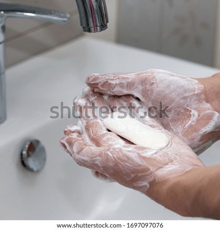 A piece of white soap on a transparent stand on a yellow background. Protect against the coronavirus. Coronavirus pandemic protection by washing hands frequently. Hygiene to stop spreading coronavirus