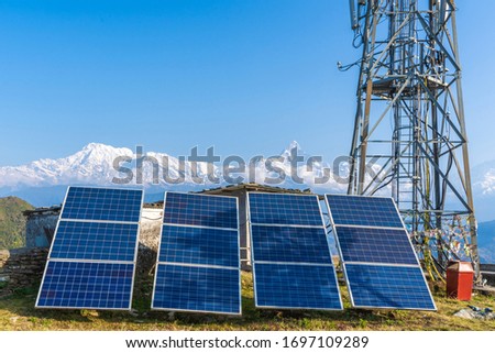 Solar panels near telecommunication tower in the mountain region. Snow covered mountain peaks on background. Green and environmentally friendly sources of energy. Stock photo
