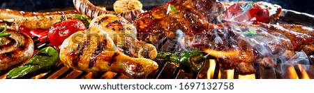 Very wide panorama banner of a large assortment of different meat and fresh vegetables grilling on a barbecue over the hot coals in close up