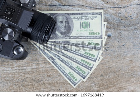 The camera and dollars on a wooden background. The concept of making money on photos
