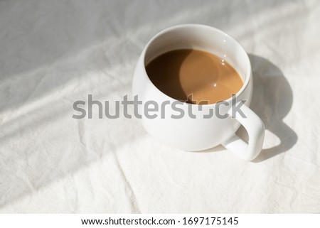 A cup of coffee on a table with shadow of sunlight.
