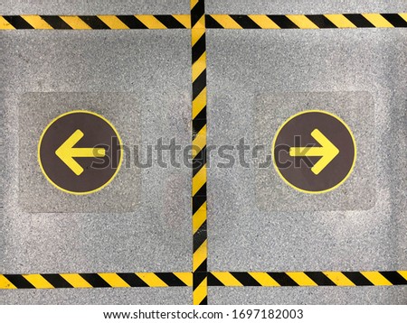 Yellow arrow sign on the floor with black and yellow stripes to keep distance of the standing in elevator 
