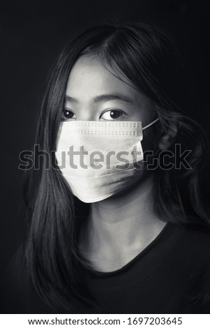 Asian young girl wearing medical face mask, studio portrait