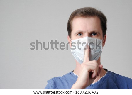 man in a sterile medical mask with a hush gesture or be quiet. professional non-disclosure secret and scary diagnosis concept