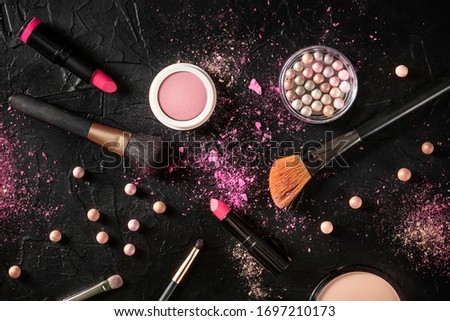Professional makeup on a black background. Brushes, lipstick and other products, a flat lay with a place for text