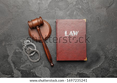 Judge's gavel, book and handcuffs on grey background
