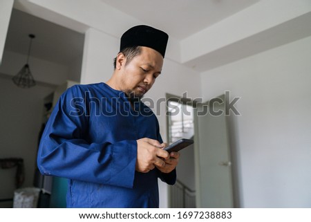 Ramadhan concept stock photo where a muslim man holding a mobile phone
