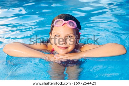 Portrait of a small smiling girl in a garden swimming pool
