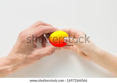 Hand of a child and an adult holding an egg on a white background