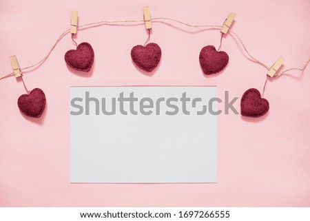 clothespins on a rope with hearts on a pink background, place for text on a white sheet, layout for a greeting card, romantic background