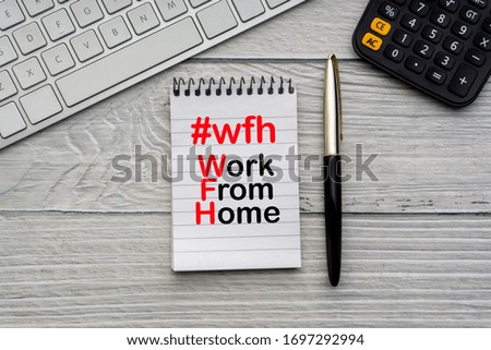 WORK FROM HOME #WFH text with notepad, keyboard, fountain pen and calculator on wooden background. Business and Healthcare concept