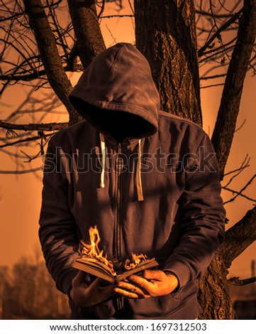 Man reading a book on fire. Reading concept. Without face. He looks at a book burning in his hands.