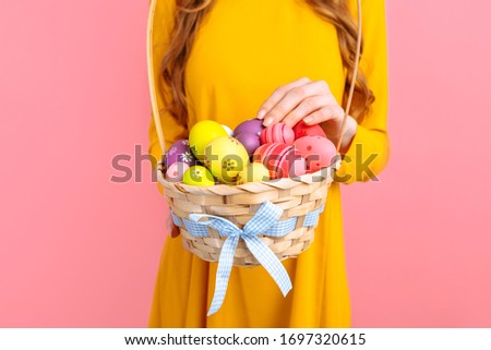 Hands hold a basket with colorful Easter eggs on an isolated pink background. happy Easter