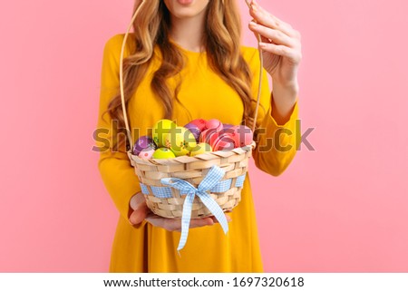 Hands hold a basket with colorful Easter eggs on an isolated pink background. happy Easter