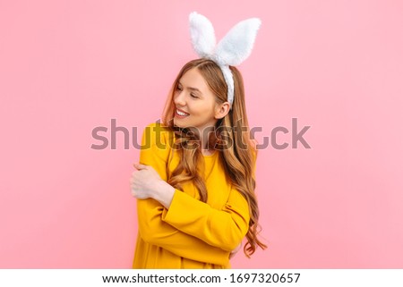 Holiday season of rabbit and eggs. Happy stylish woman in Easter Bunny ears isolated on pink background.
