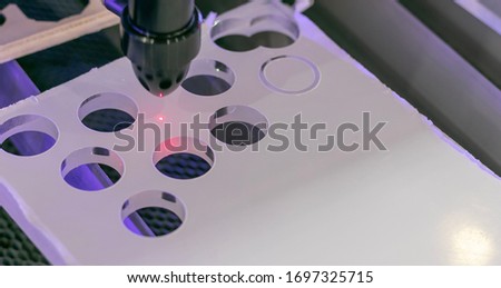 Details of an industrial cnc laser cutting machine. Drilling holes in plexyglass panel with hot plasma pin head. Automation concept, robotic arm, future jobs concept. 